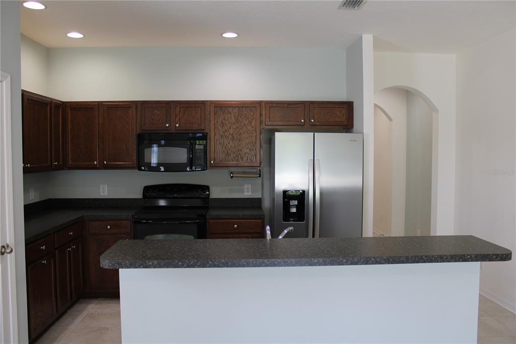 A kitchen features dark wood cabinets, black countertops, stainless steel appliances, and a breakfast bar — 5024 119TH TERRACE E, PARRISH, FL