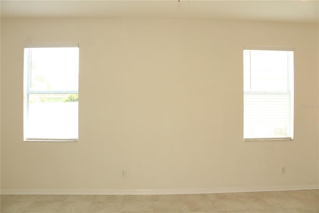An empty room with beige walls, tile flooring, and two windows with white blinds — 5024 119TH TERRACE E, PARRISH, FL