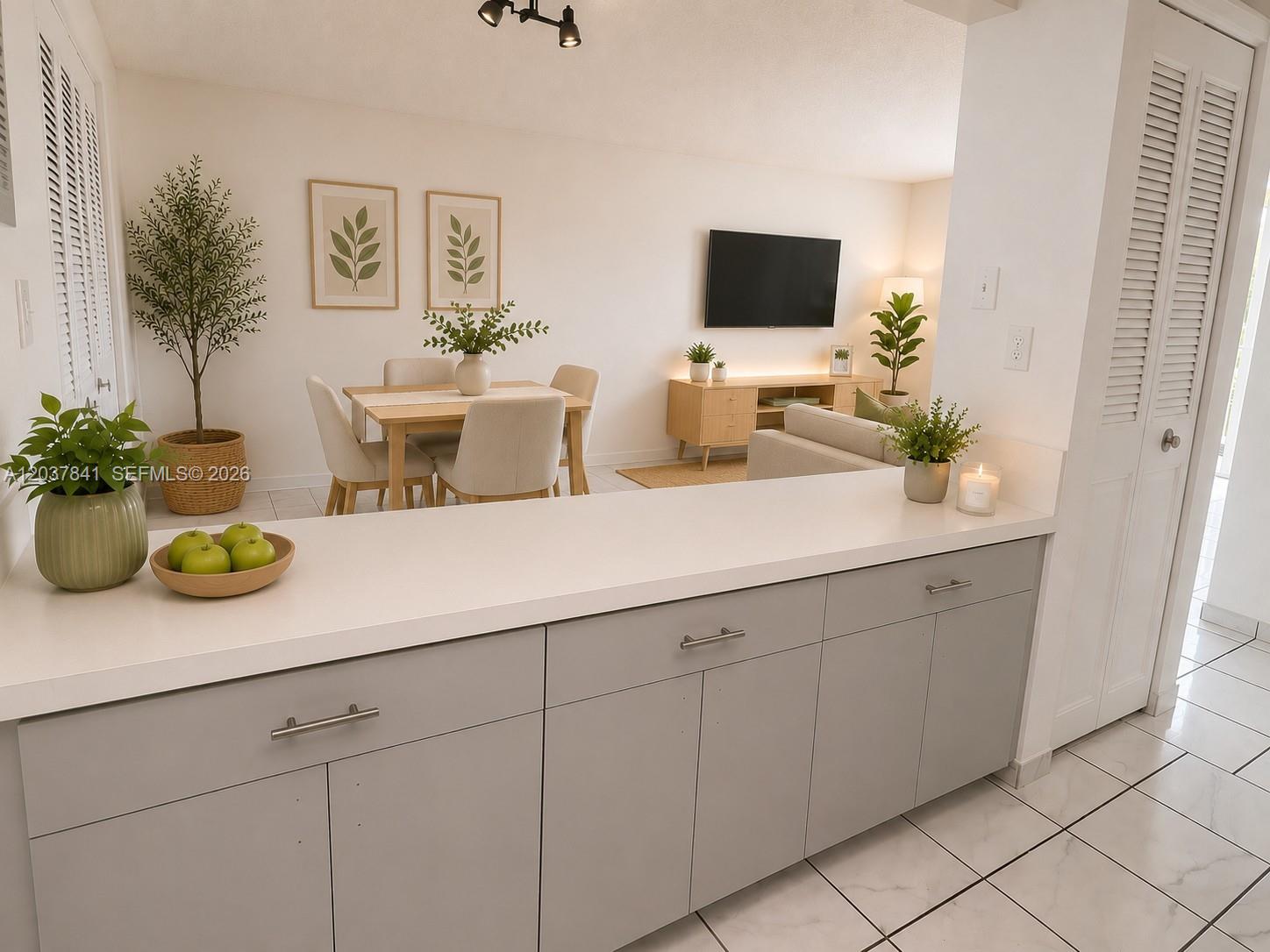 A kitchen counter with gray cabinets overlooks a dining area and living room — 820 NW 87th Ave # 201, Miami FL 33172, MIAMI, FL
