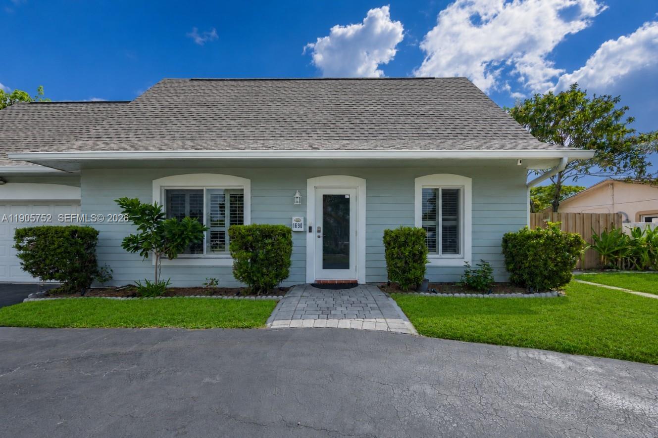 A light blue, single-story house with a gray shingled roof and a paved walkway — 1690 NE 25th Ave, Pompano Beach FL 33062, POMPANO BEACH, FL