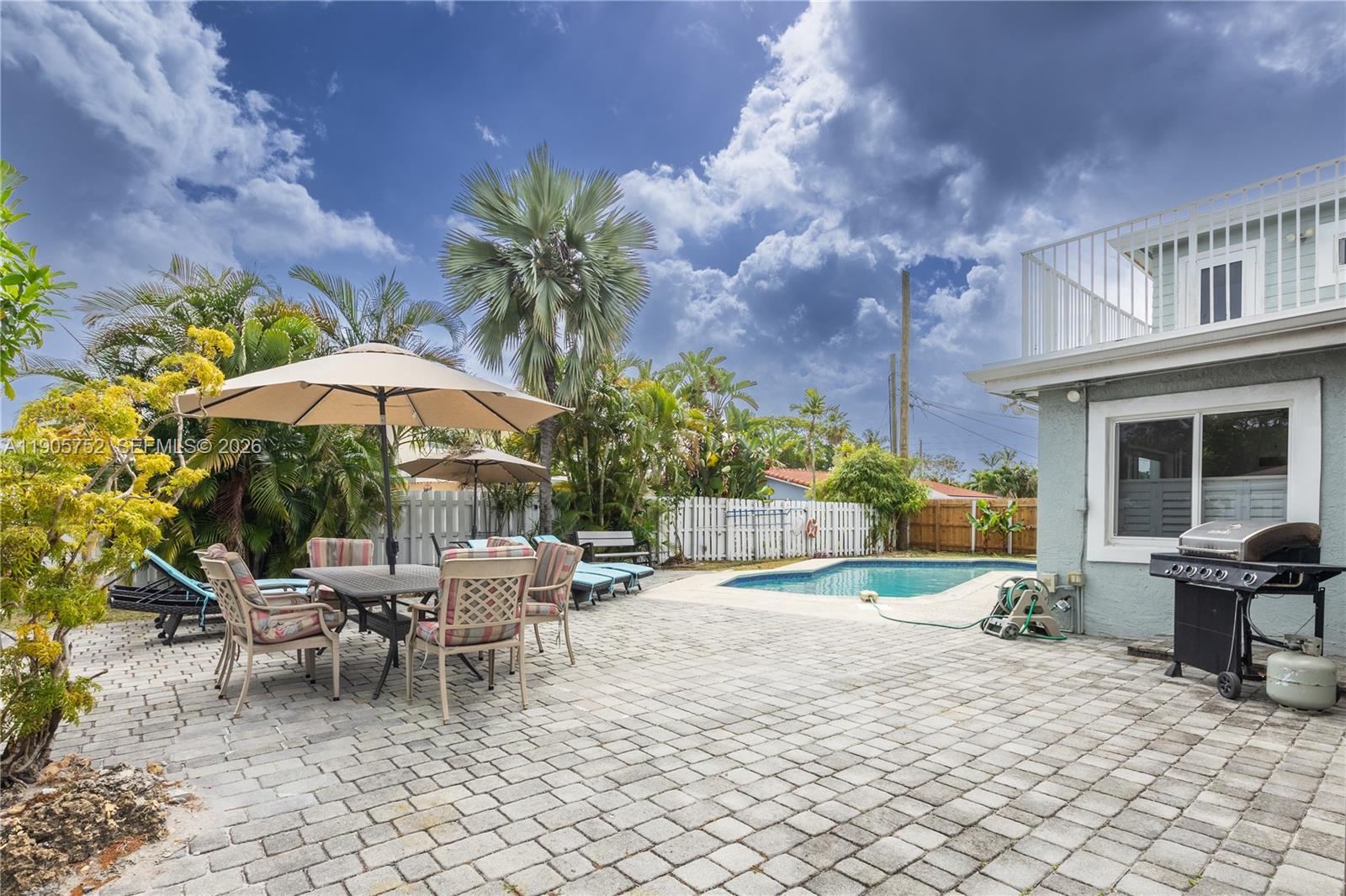 A backyard patio features a dining set, a swimming pool, and a gas grill — 1690 NE 25th Ave, Pompano Beach FL 33062, POMPANO BEACH, FL