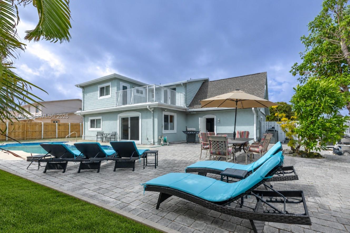 A backyard features a swimming pool, a paved patio with lounge chairs, and a two-story house — 1690 NE 25th Ave, Pompano Beach FL 33062, POMPANO BEACH, FL