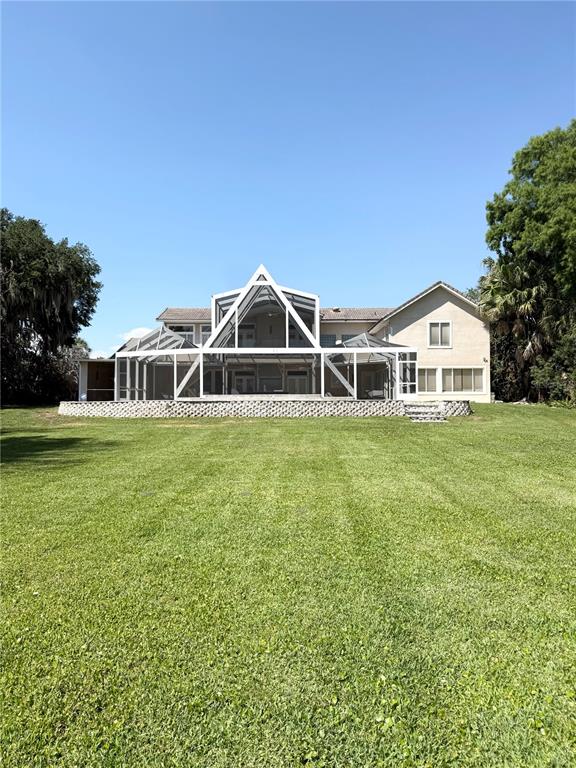 A large two-story house features a prominent white screened-in patio overlooking a grassy lawn — 1890 SAHA COURT, KISSIMMEE, FL
