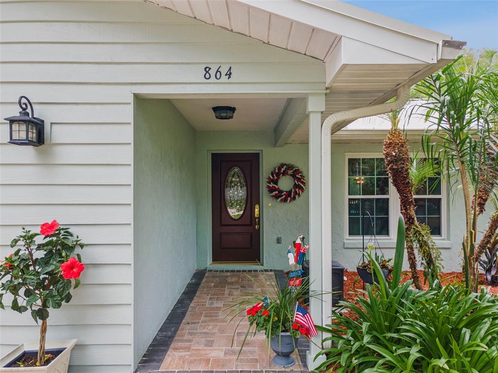 A front entryway features a dark brown door, a brick walkway, and light green siding — 864 REDWOOD WAY, LAKE WALES, FL