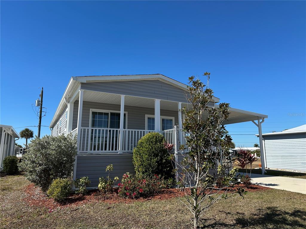 A light gray manufactured home features a front porch with white railings and a carport — 330 TRAILORAMA DRIVE, NORTH PORT, FL