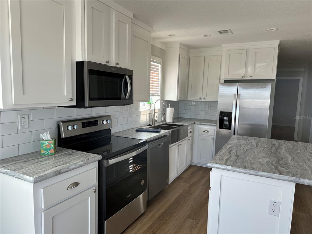 A kitchen with white cabinets, stainless steel appliances, and gray patterned countertops — 330 TRAILORAMA DRIVE, NORTH PORT, FL