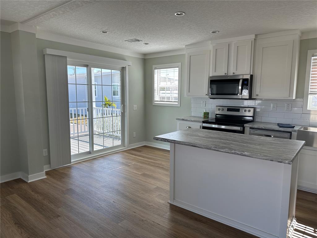 A kitchen with white cabinets, a gray island, and a sliding glass door to a deck — 330 TRAILORAMA DRIVE, NORTH PORT, FL