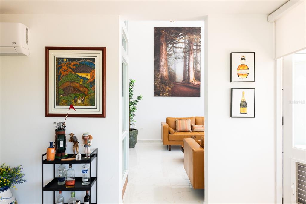 A bar cart stands in a white hallway leading to a living room with leather furniture — 91 VILLAS DE GOLF EAST, DORADO, PR