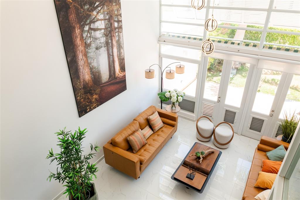 A high-angle view of a modern living room with leather sofas, tile floors, and tall windows — 91 VILLAS DE GOLF EAST, DORADO, PR