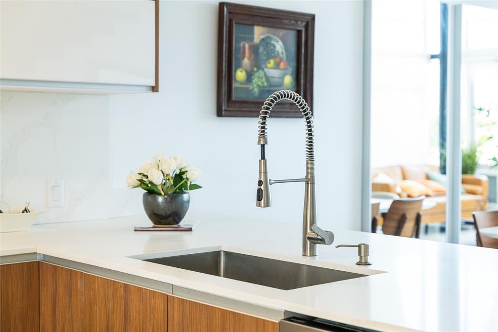A modern kitchen island features a stainless steel sink, a gooseneck faucet, and white countertops — 91 VILLAS DE GOLF EAST, DORADO, PR