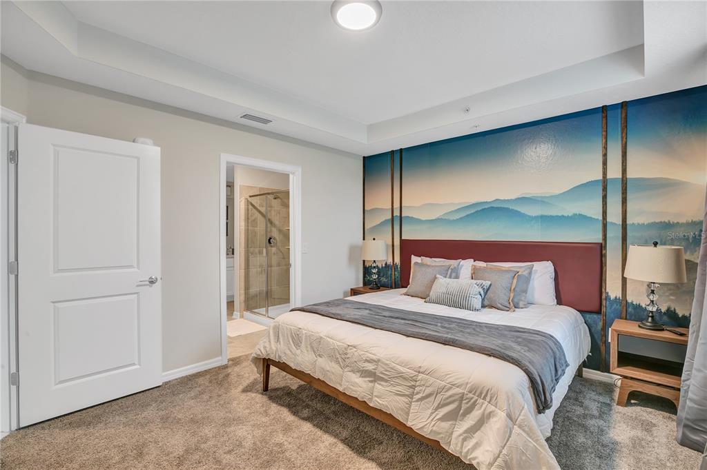 A bedroom features a mountain mural, a bed with a red headboard, and an attached bathroom — 4721 CLOCK TOWER DRIVE UNIT 108, KISSIMMEE, FL