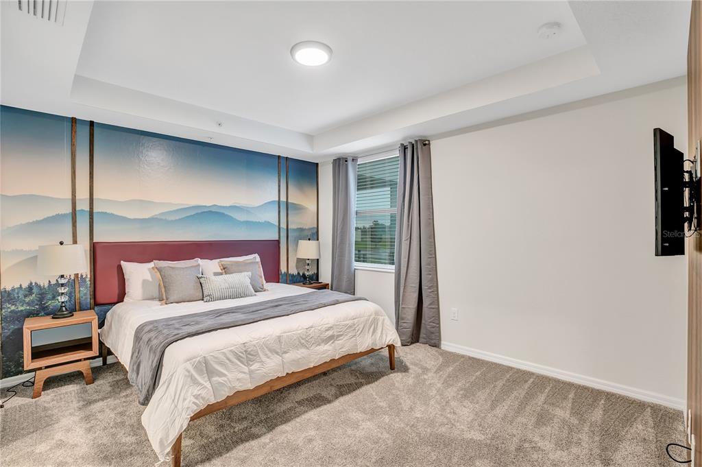 A bedroom features a mountain mural, a bed with a red headboard, and gray carpeting — 4721 CLOCK TOWER DRIVE UNIT 108, KISSIMMEE, FL