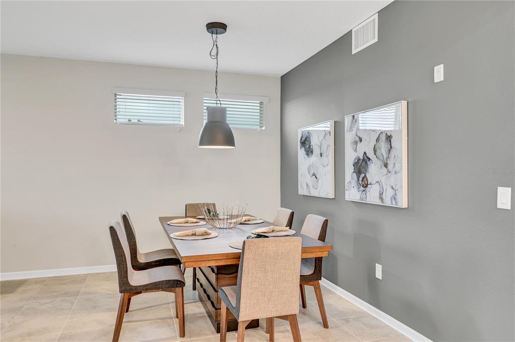 A dining room features a wooden table, six chairs, a pendant light, and gray accent wall — 4721 CLOCK TOWER DRIVE UNIT 108, KISSIMMEE, FL