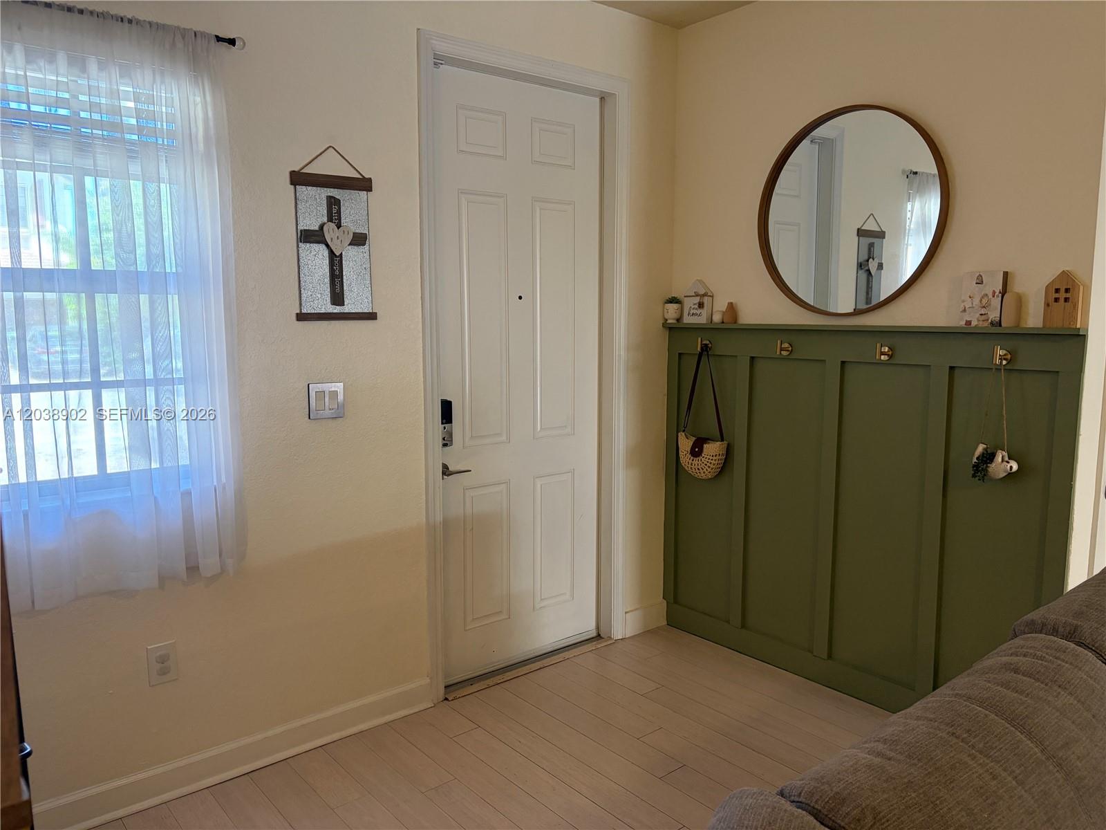 An entryway features a white door, a green paneled wall with hooks, and a round mirror — 370 NE 37th Pl, Homestead FL 33033, HOMESTEAD, FL