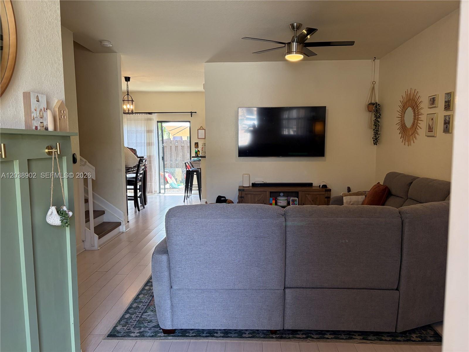 A living room features a gray sectional sofa, a wall-mounted television, and light wood flooring — 370 NE 37th Pl, Homestead FL 33033, HOMESTEAD, FL