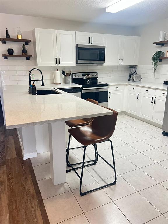 A kitchen features white cabinets, quartz countertops, a subway tile backsplash, and two bar stools — 8837 GRAND PALMS CIRCLE UNIT A, KISSIMMEE, FL