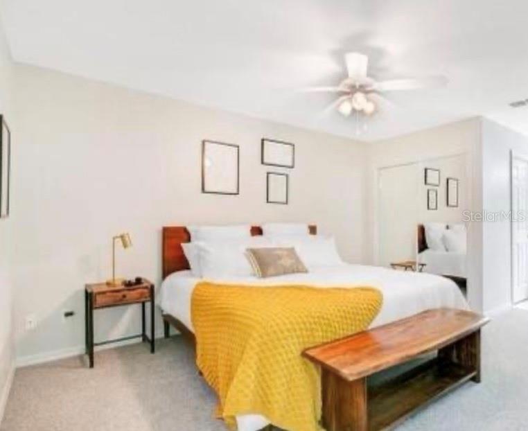 A bedroom features a bed with a yellow throw, a wooden bench, and a nightstand — 8837 GRAND PALMS CIRCLE UNIT A, KISSIMMEE, FL