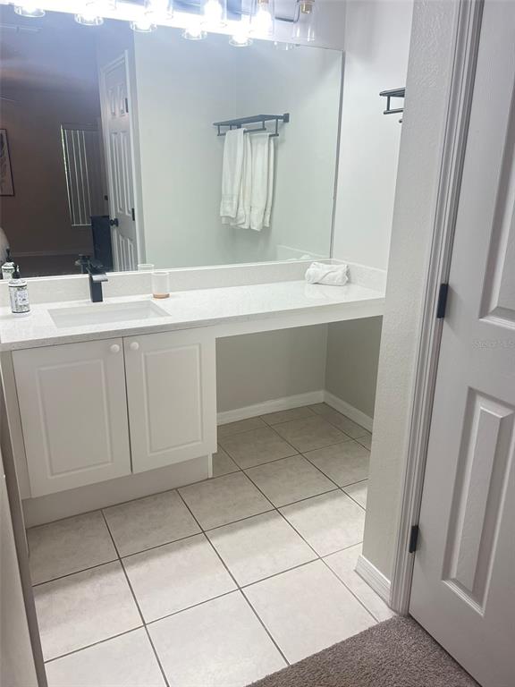 A bathroom features a white vanity with a single sink, a mirror, and tiled flooring — 8837 GRAND PALMS CIRCLE UNIT A, KISSIMMEE, FL
