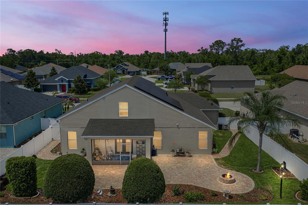 The rear exterior of a house features a screened-in patio, paver terrace, and fire pit — 1713 VIA PALERMO STREET, PLANT CITY, FL