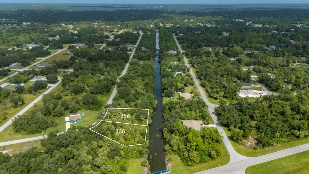 An aerial view shows two adjacent wooded lots bordering a canal in a residential area — 356 & 366 FERDON CR. CIRCLE, PORT CHARLOTTE, FL