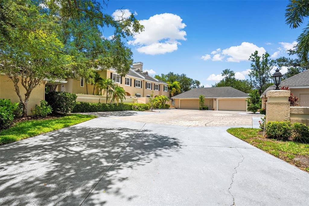 A large concrete driveway leads to a detached garage and a multi-story residential building — 13770 MARSEILLES COURT, CLEARWATER, FL