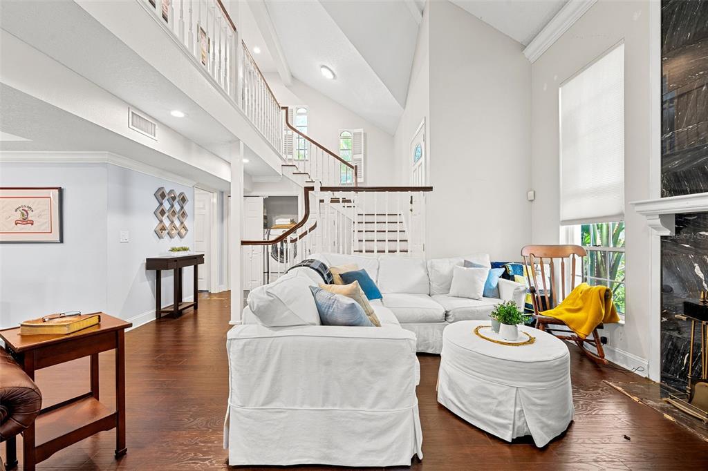 A living room features a white sectional sofa, a staircase, and a black marble fireplace — 13770 MARSEILLES COURT, CLEARWATER, FL