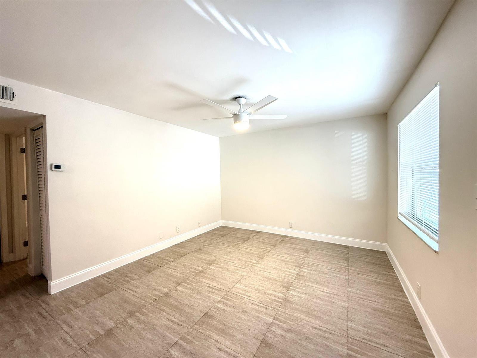 An empty room features light-colored walls, a ceiling fan, and large, wood-look tile flooring — 607 NE 29th Drive # 22, Wilton Manors FL 33334, WILTON MANORS, FL