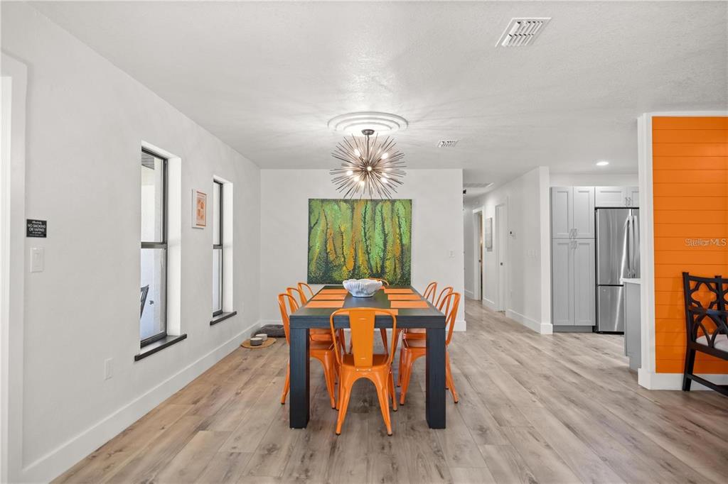 A dining room features a dark table with orange chairs, wood-look flooring, and a chandelier — 10380 NW 21ST STREET, OCALA, FL