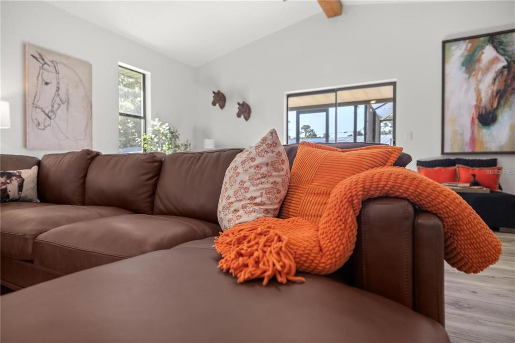 A living room features a large brown sectional sofa with orange accents and horse-themed artwork — 10380 NW 21ST STREET, OCALA, FL