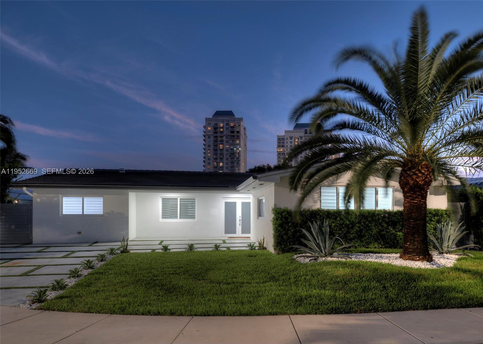 A single-story white house with a palm tree and a paved driveway at dusk — 1250 NE 82nd St, Miami FL 33138, MIAMI, FL