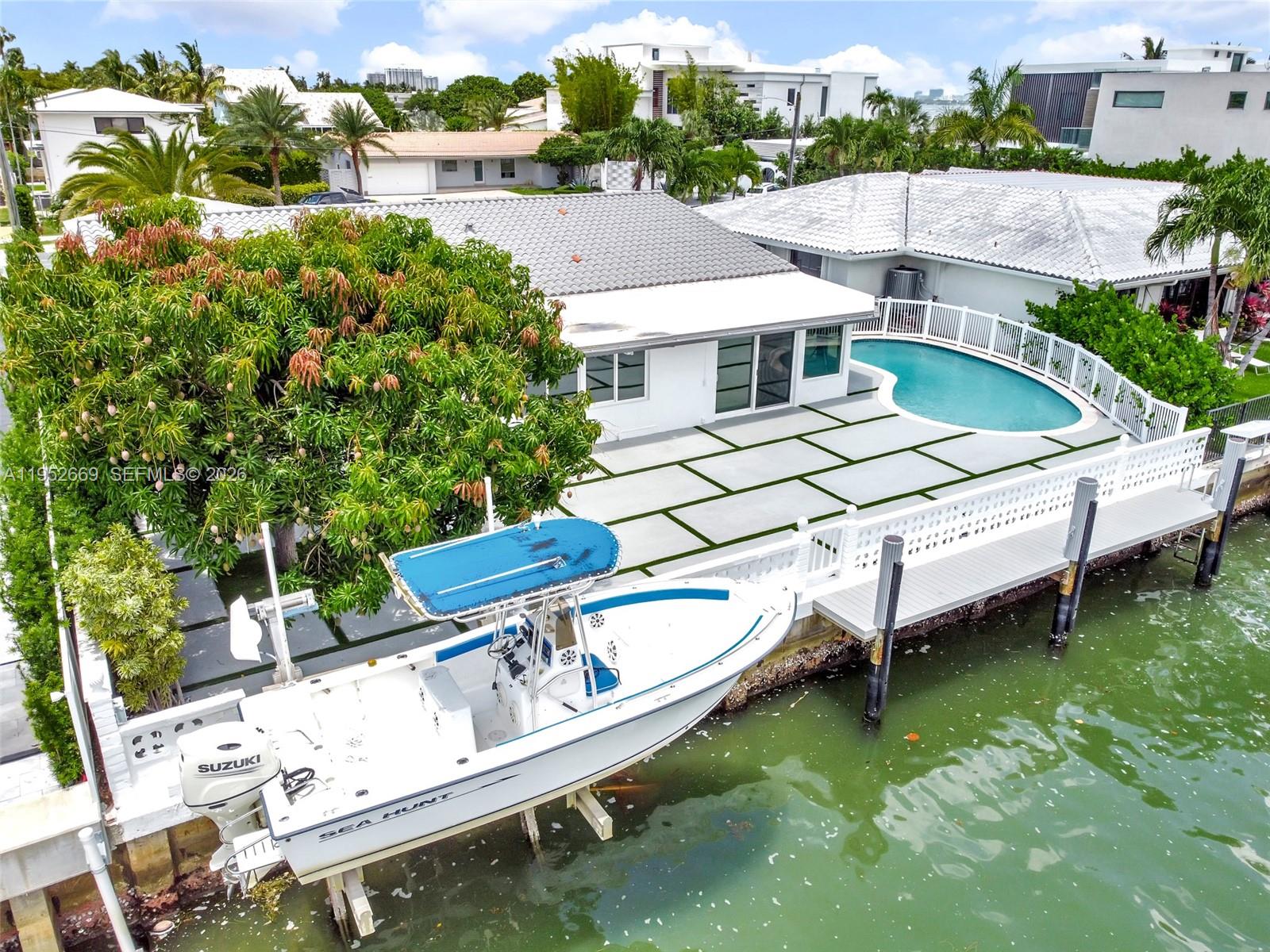 An aerial view shows a waterfront house with a pool, patio, and boat lift — 1250 NE 82nd St, Miami FL 33138, MIAMI, FL