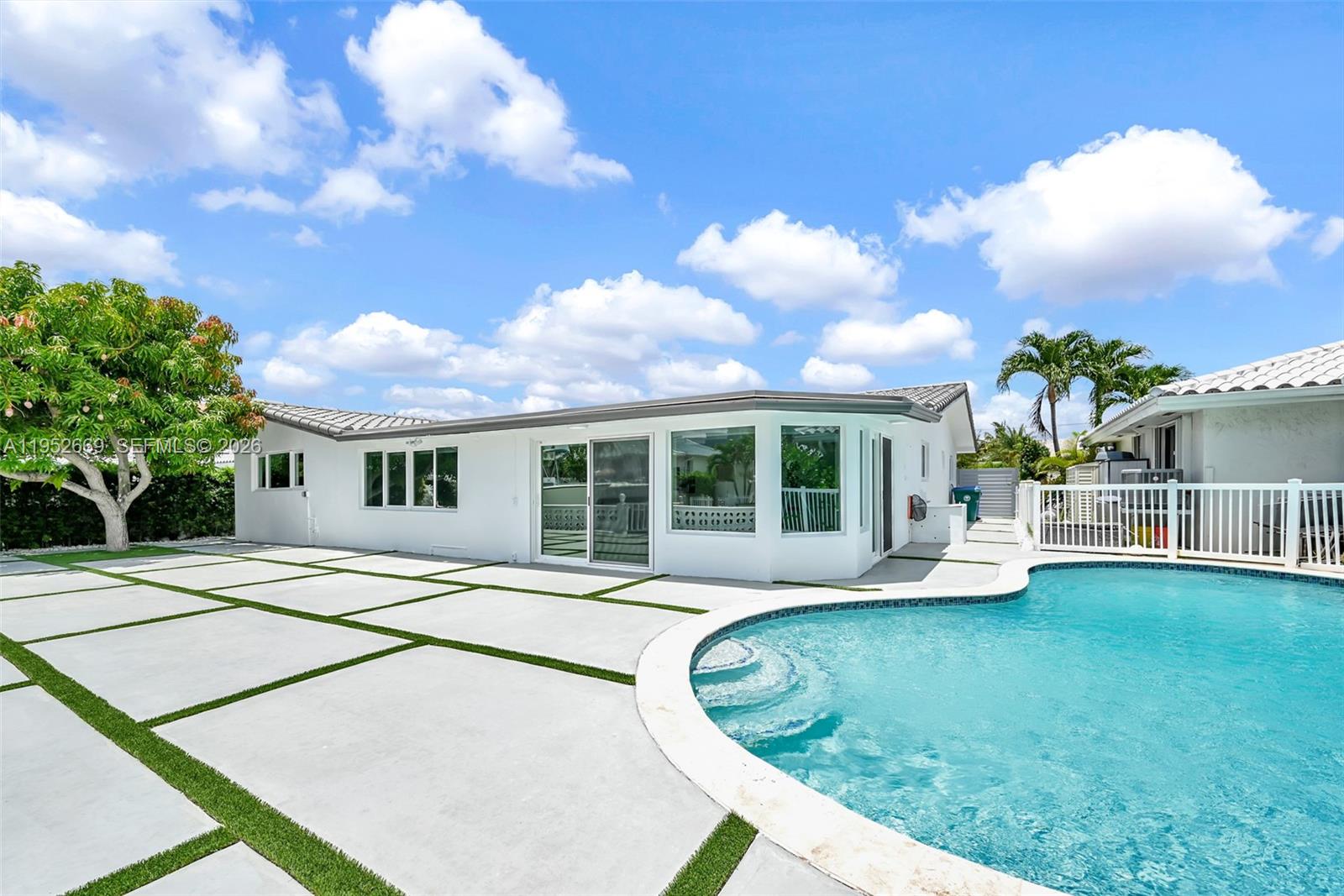 A white house exterior features a patio with concrete pavers and a swimming pool — 1250 NE 82nd St, Miami FL 33138, MIAMI, FL
