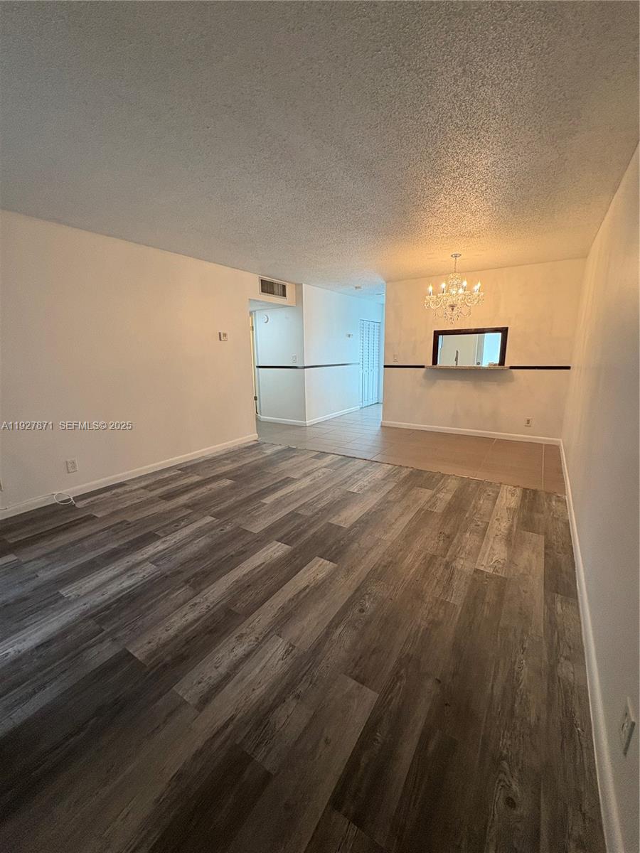 An open living area features wood-look flooring, a tiled dining space, and a crystal chandelier — 4441 NW 16th St # J102, Lauderhill FL 33313, LAUDERHILL, FL