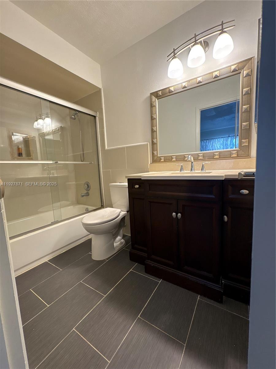 A bathroom features a dark wood vanity, a framed mirror, and a tiled shower enclosure — 4441 NW 16th St # J102, Lauderhill FL 33313, LAUDERHILL, FL