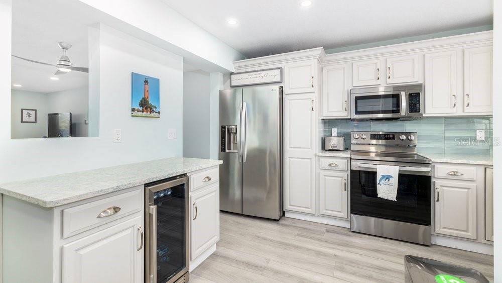 A kitchen features white cabinets, stainless steel appliances, a wine cooler, and light-colored countertops — 4783 S ATLANTIC AVENUE UNIT E2, PORT ORANGE, FL