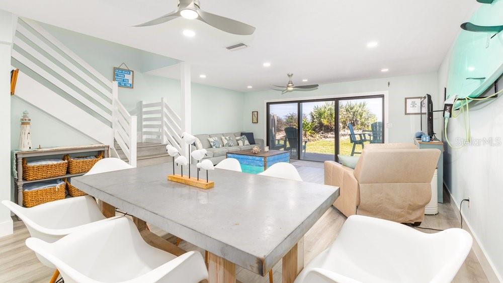 A dining area with a concrete table leads to a living room with sliding glass doors — 4783 S ATLANTIC AVENUE UNIT E2, PORT ORANGE, FL