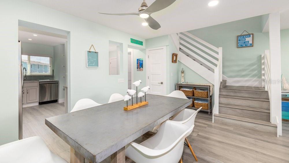 A dining room with a concrete table, white chairs, and stairs leading to an upper level — 4783 S ATLANTIC AVENUE UNIT E2, PORT ORANGE, FL