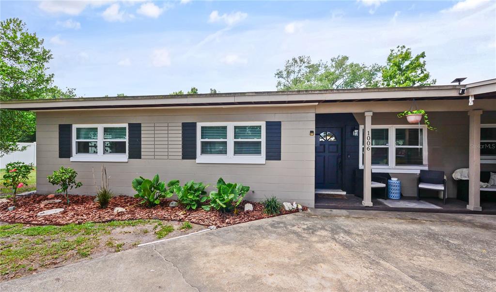 The exterior of a single-story house features gray horizontal siding, black shutters, and a concrete driveway — 1006 BEATRICE DRIVE, ORLANDO, FL