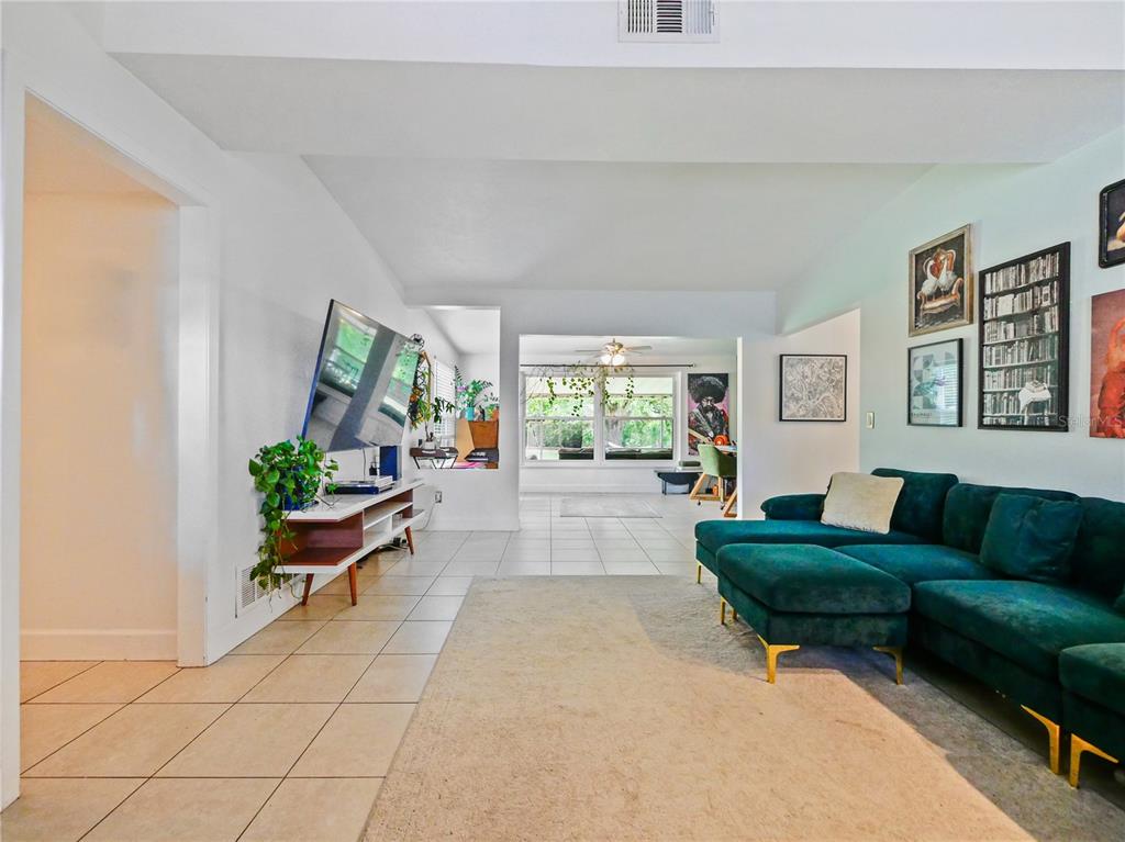 A living room features a teal sectional sofa, a television on a stand, and tile flooring — 1006 BEATRICE DRIVE, ORLANDO, FL