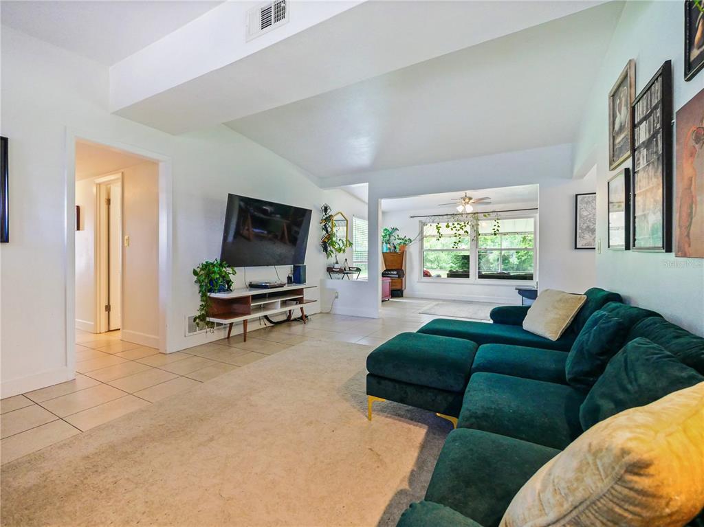 A living room features a green sectional sofa, a wall-mounted television, and tiled flooring — 1006 BEATRICE DRIVE, ORLANDO, FL