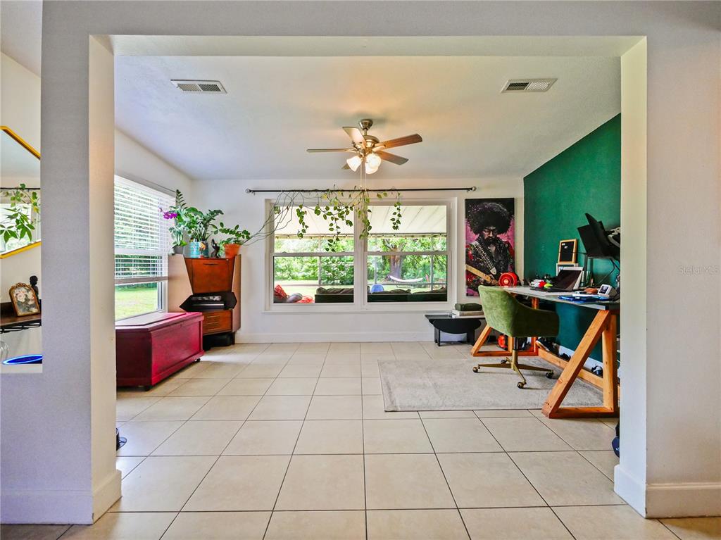 A room with tiled floors, a green accent wall, a desk, and a ceiling fan — 1006 BEATRICE DRIVE, ORLANDO, FL