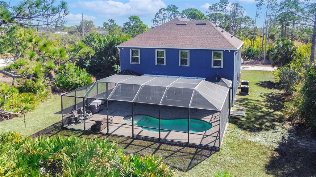 An aerial view of a blue two-story house with a screened-in pool and patio — 9219 CANNA STREET, PORT CHARLOTTE, FL