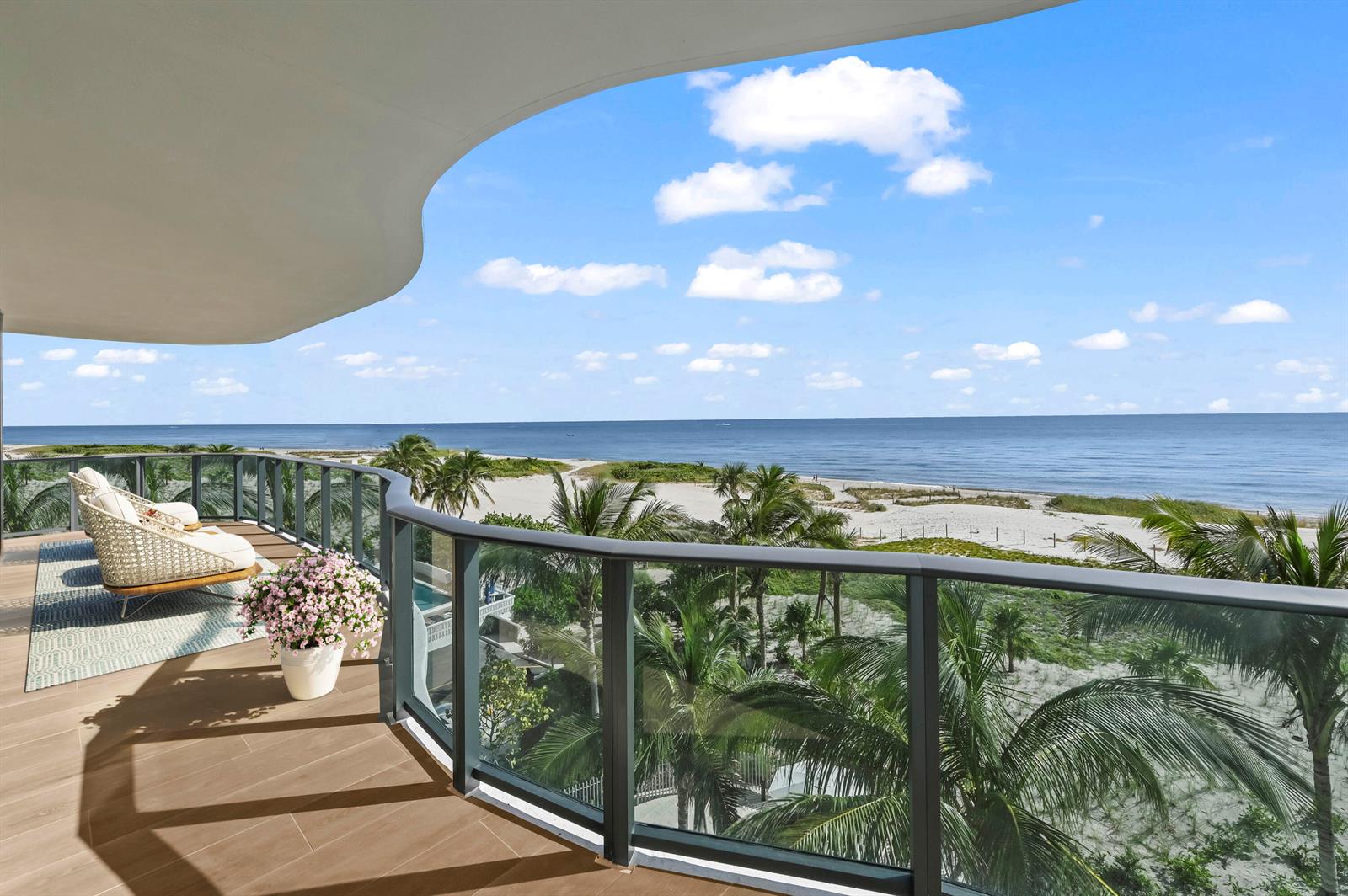 A curved balcony with outdoor seating overlooks a sandy beach, palm trees, and the ocean — 900 N Ocean Boulevard # 406, Pompano Beach FL 33062, POMPANO BEACH, FL