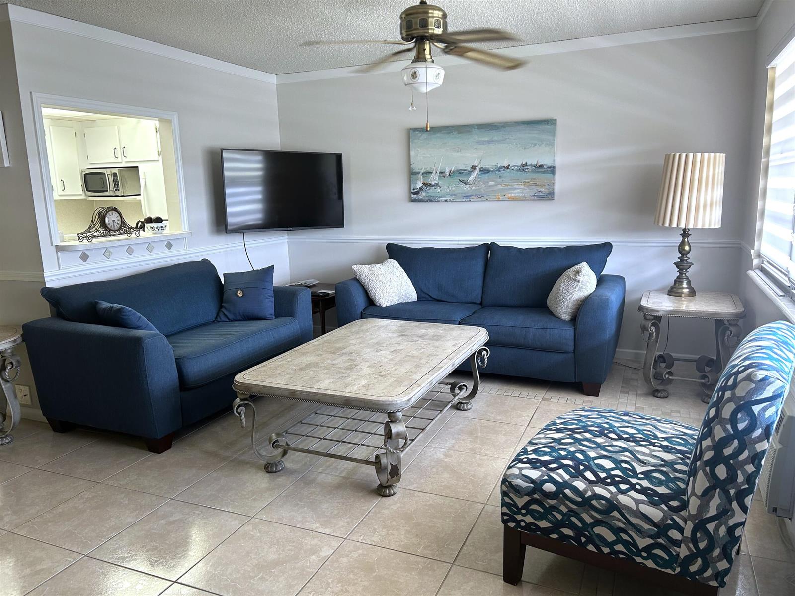 A living room features two blue sofas, a patterned chair, and a stone coffee table — 335 Farnham P, Deerfield Beach FL 33442, DEERFIELD BEACH, FL