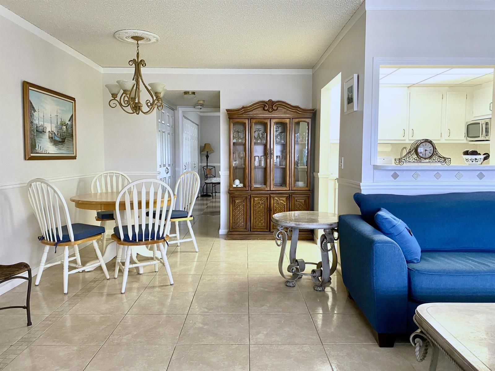 A dining area with a wooden hutch and table sits next to a blue sofa — 335 Farnham P, Deerfield Beach FL 33442, DEERFIELD BEACH, FL