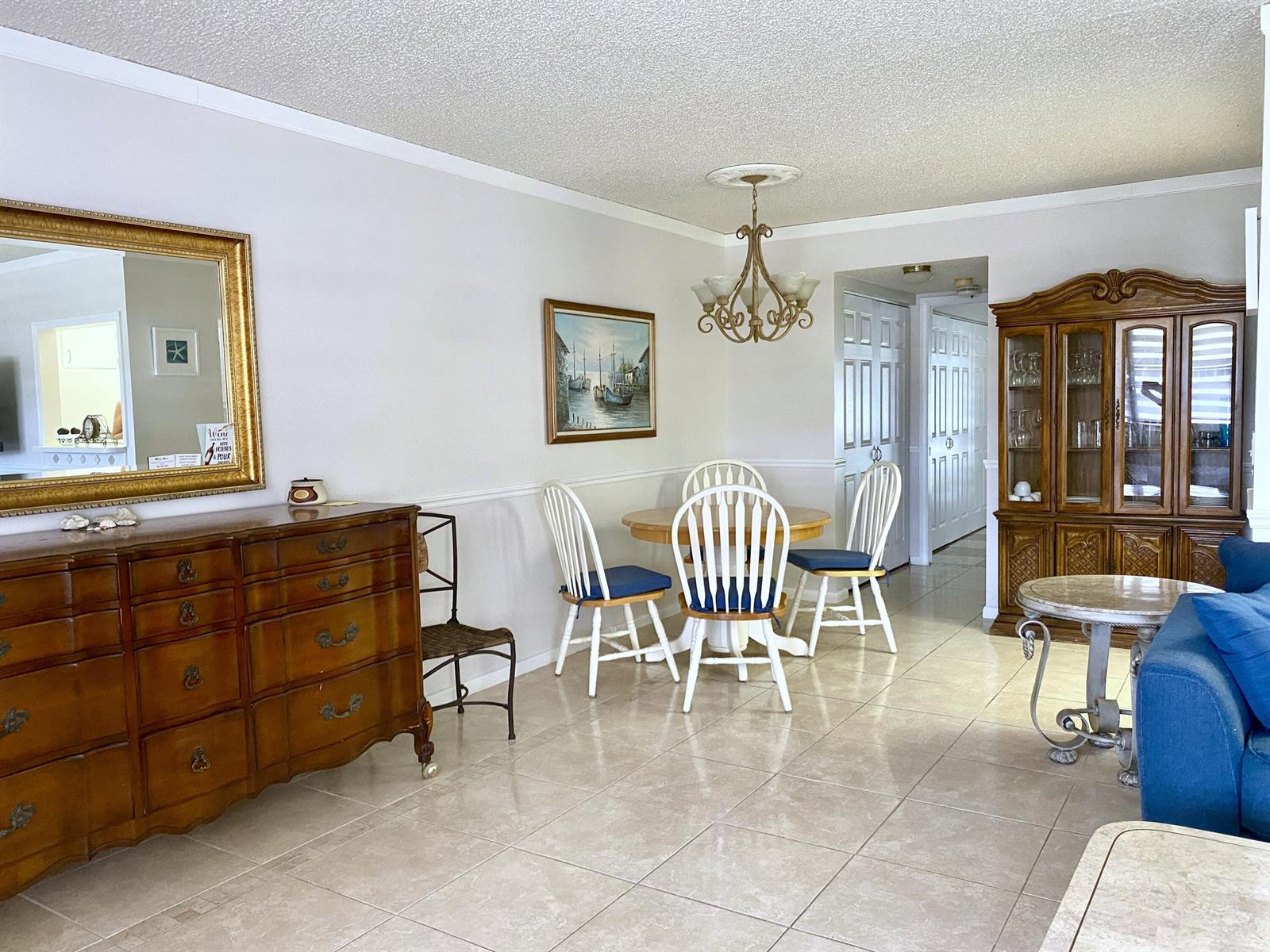 A dining area with a wooden hutch, round table, white chairs, and tile flooring — 335 Farnham P, Deerfield Beach FL 33442, DEERFIELD BEACH, FL