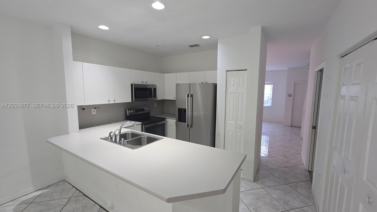 A kitchen features white cabinets, stainless steel appliances, and a peninsula with a sink — 5791 NW 116th Ave # 101, Doral FL 33178, DORAL, FL