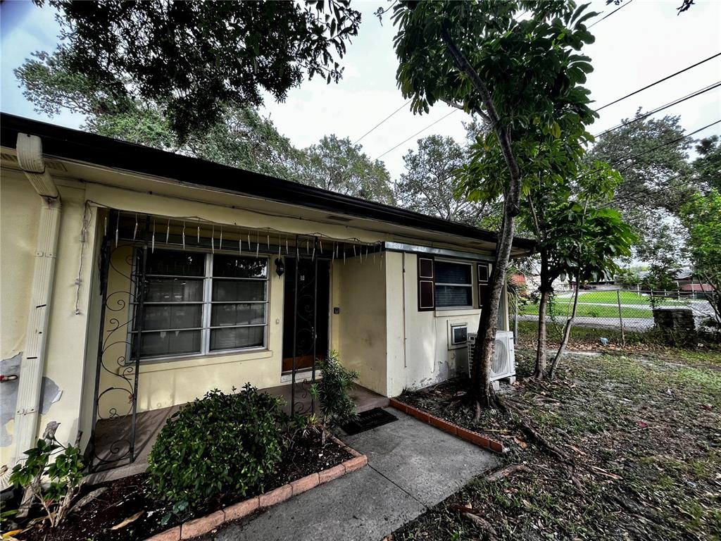 A single-story house with a yellow exterior, metal window awnings, and a small front yard — 1411 KENNYWOOD DRIVE Apt B, LARGO, FL