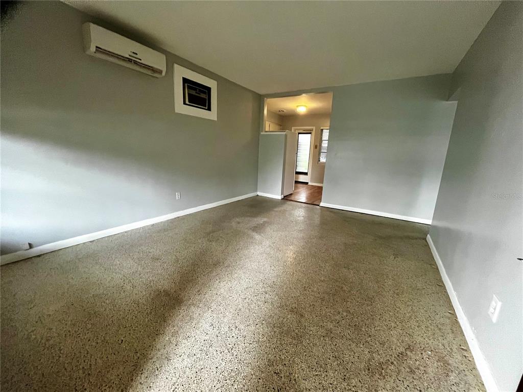 An empty room with gray walls, a concrete floor, and a wall-mounted air conditioner — 1411 KENNYWOOD DRIVE Apt B, LARGO, FL