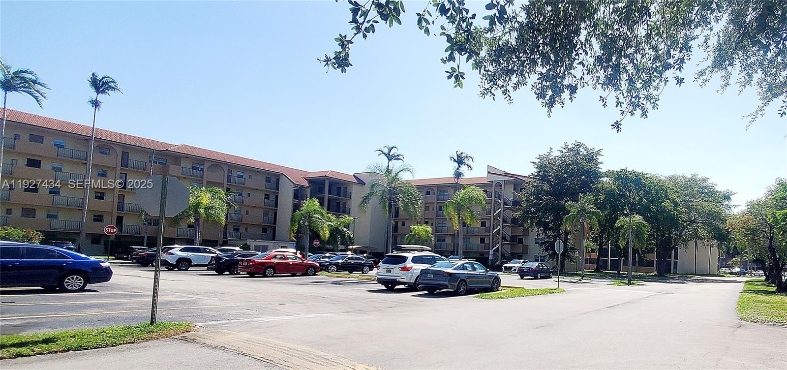 A multi-story apartment building stands behind a parking lot filled with various parked cars — 3905 N Nob Hill Rd # 510, Sunrise FL 33351, SUNRISE, FL